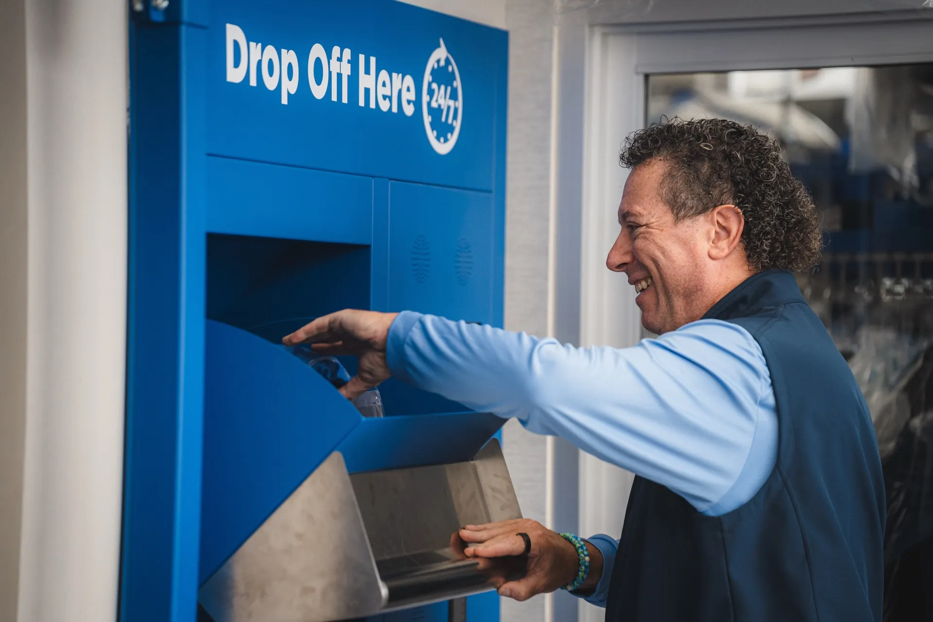 Customer dropping off garments at the Tres Bon 24/7 drop-off kiosk