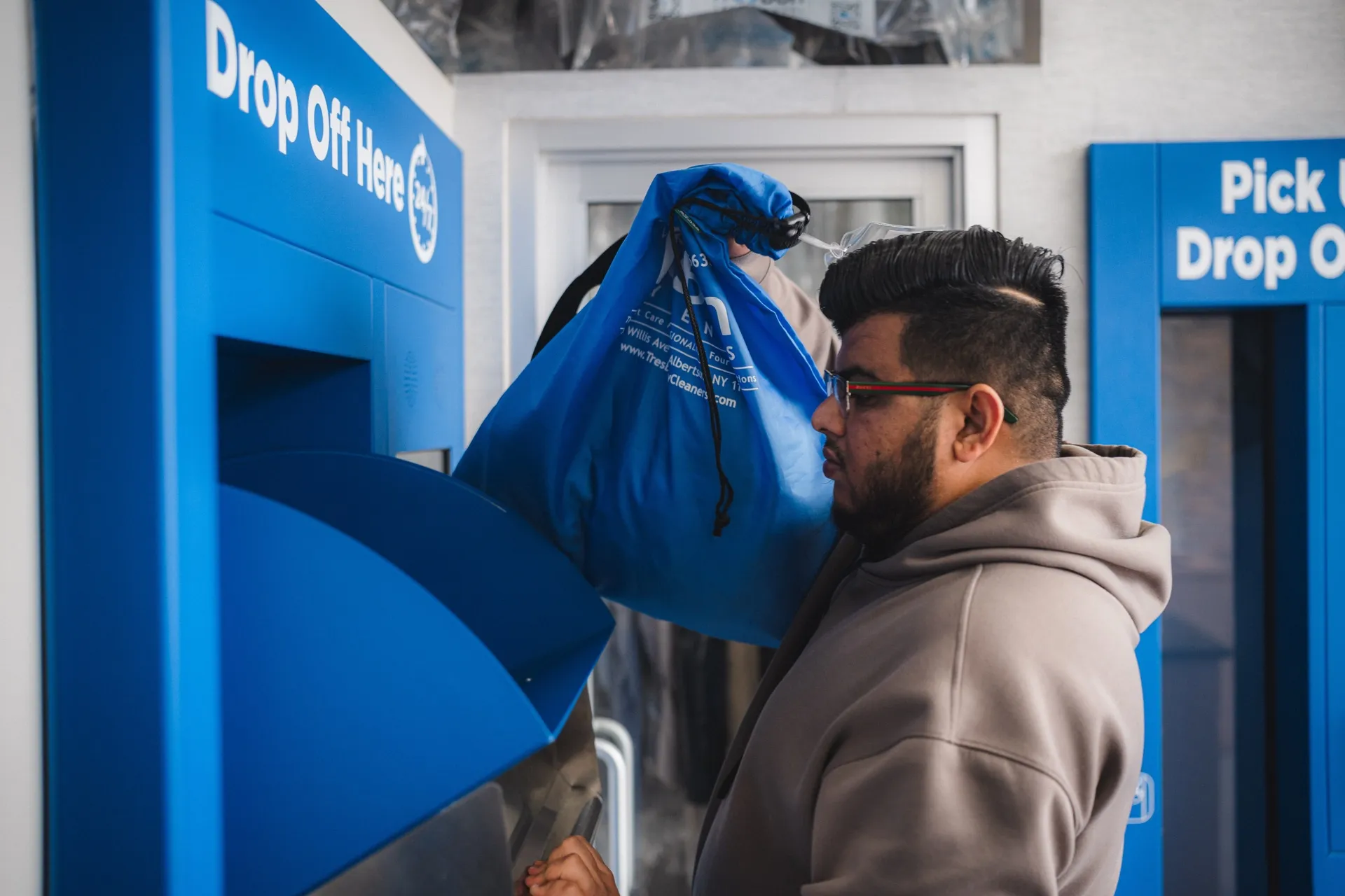Customer placing a garment bag in the Tres Bon drop-off kiosk